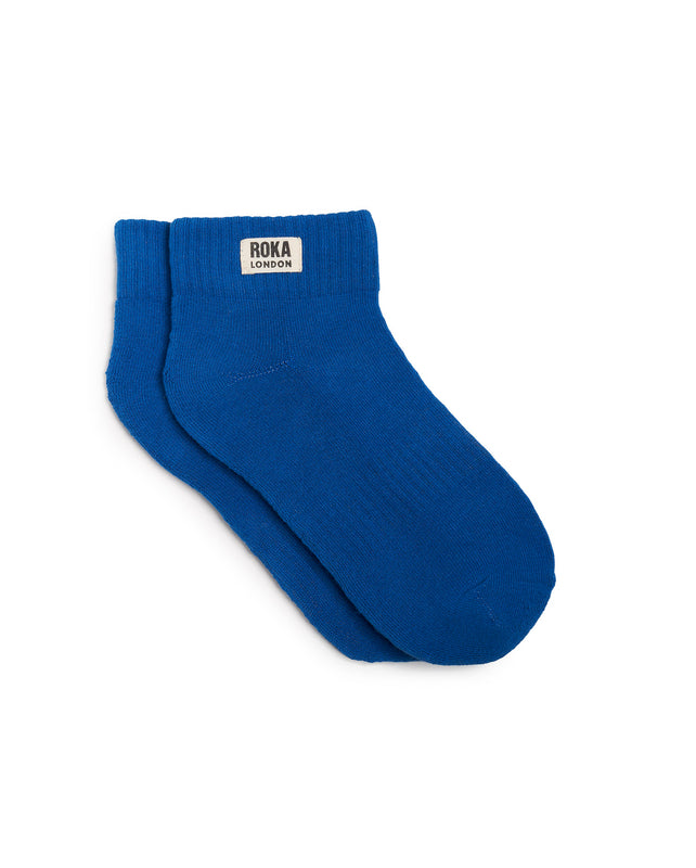 A pair of bright blue socks with the brand name 'Roka' visible on the ankle area.